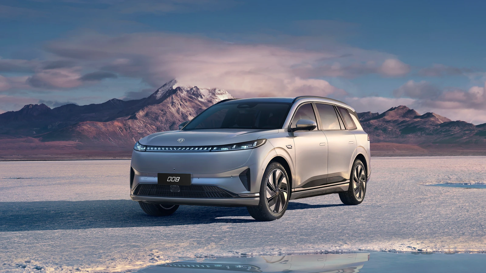 Dongfeng 008 ante un paisaje de montañas al atardecer; imagen internacional con llantas de otro diseño
