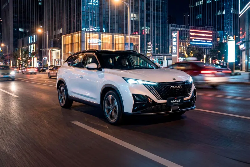 Dongfeng Mage blanco con techo negro andando por una avenida de noche